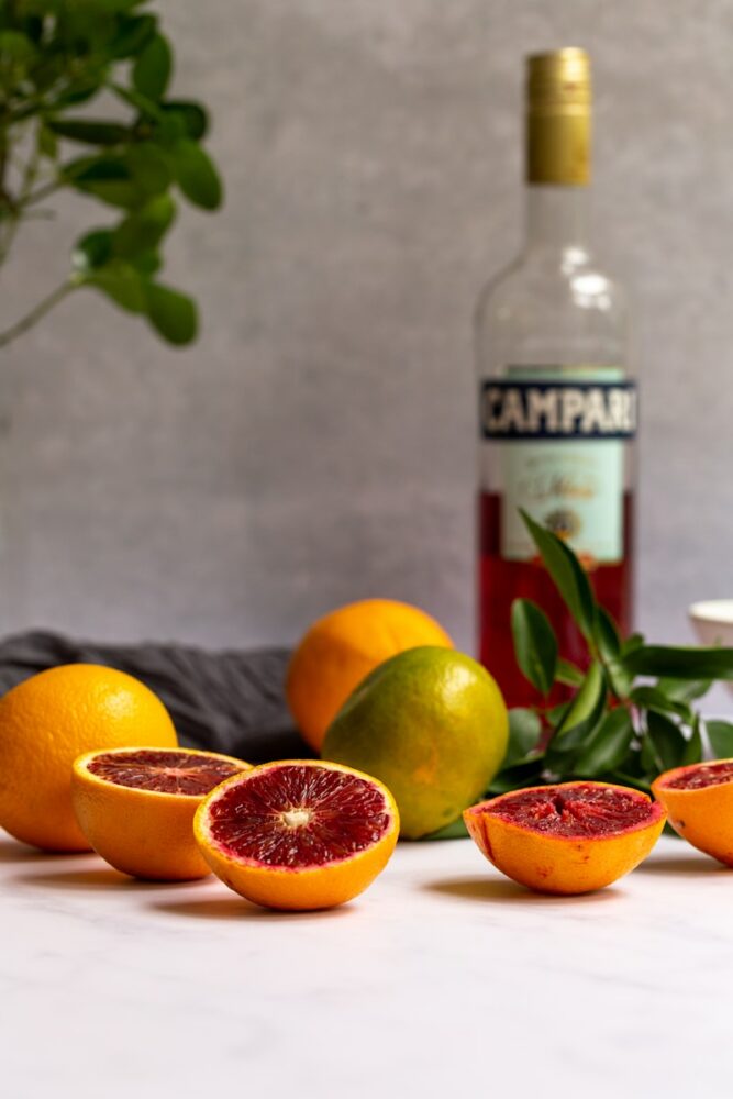 grapefruits, oranges, and a bottle of wine on a counter